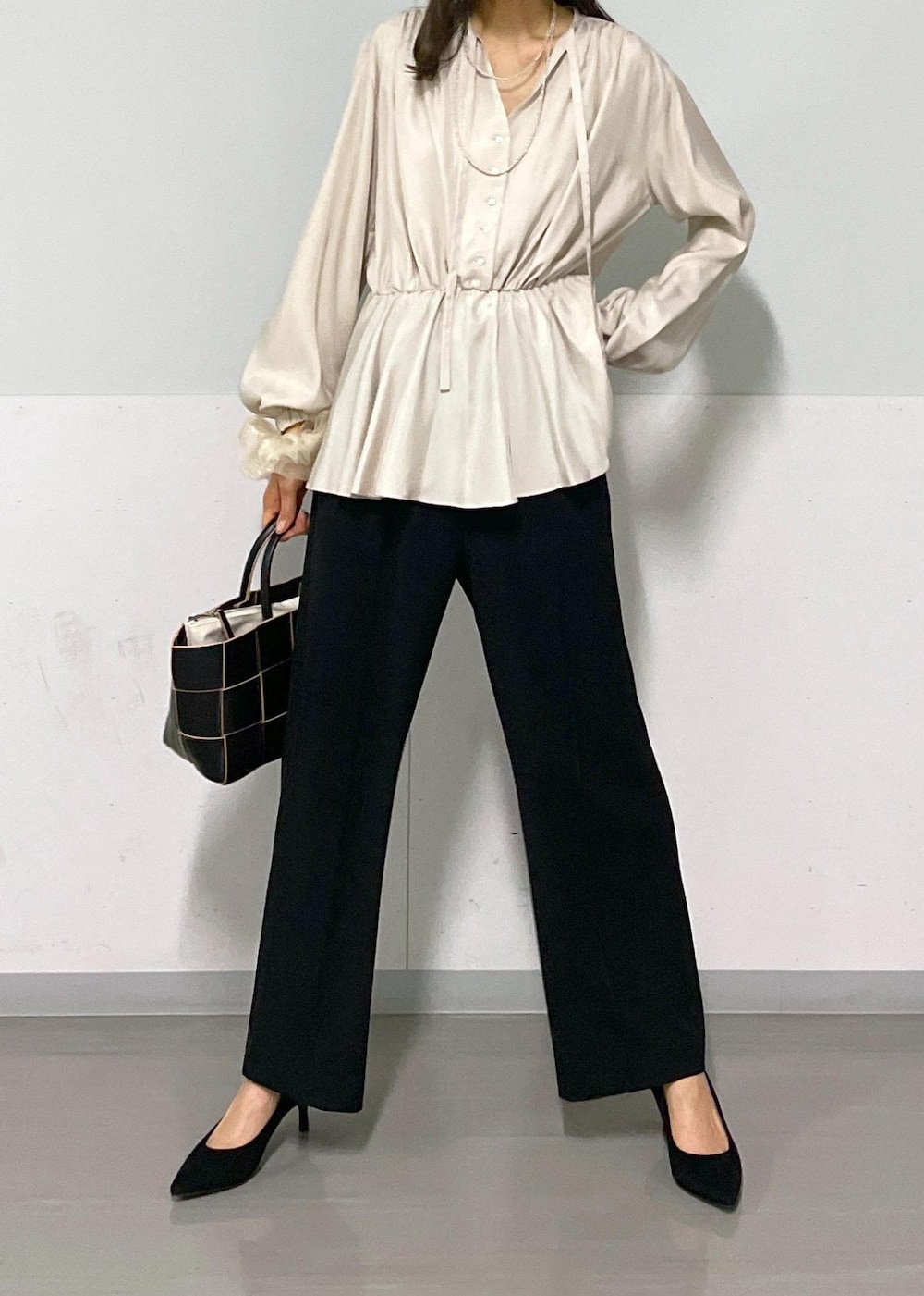ブラック系のトートバッグ、ブラック系のスラックス、ベージュ系のシャツ/ブラウスを着用したレディースの春コーディネートの7枚目の写真