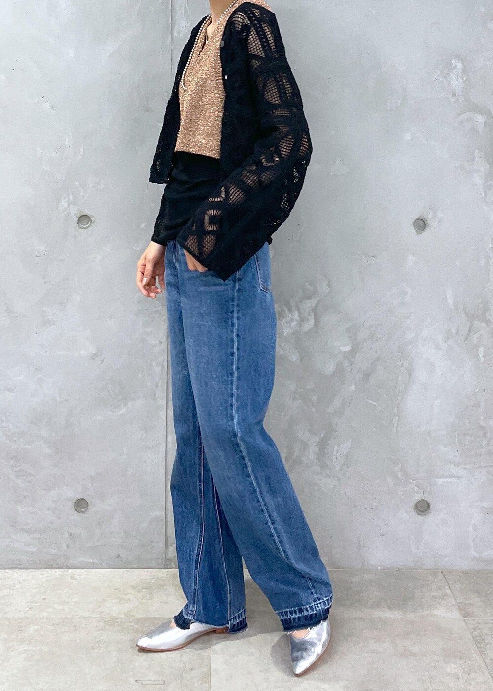 ブラック系のショルダーバッグ、ブルー系のデニムパンツ、ゴールド系のベストを着用したレディースの春コーディネートの4枚目の写真