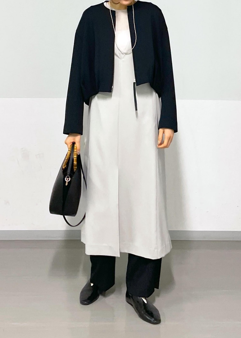 ベージュ系のジャンパースカート、ブラック系のブルゾン、ブラック系のスラックスを着用したレディースの春コーディネートの10枚目の写真