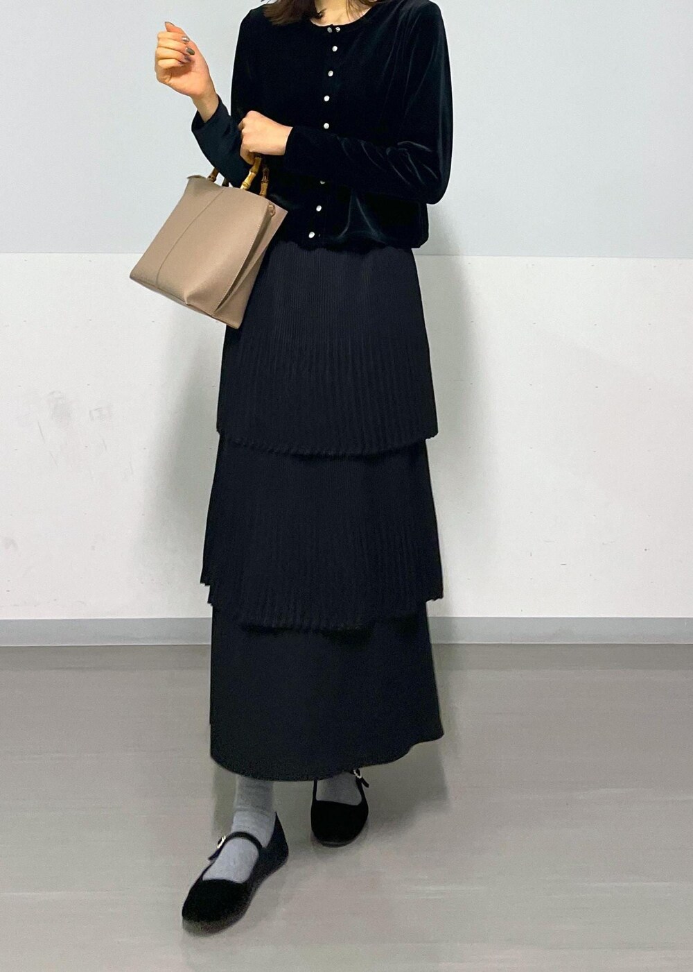 ブラック系のカーディガン/ボレロ、ブラック系のスカート、ベージュ系のハンドバッグを着用したレディースの冬コーディネートの9枚目の写真