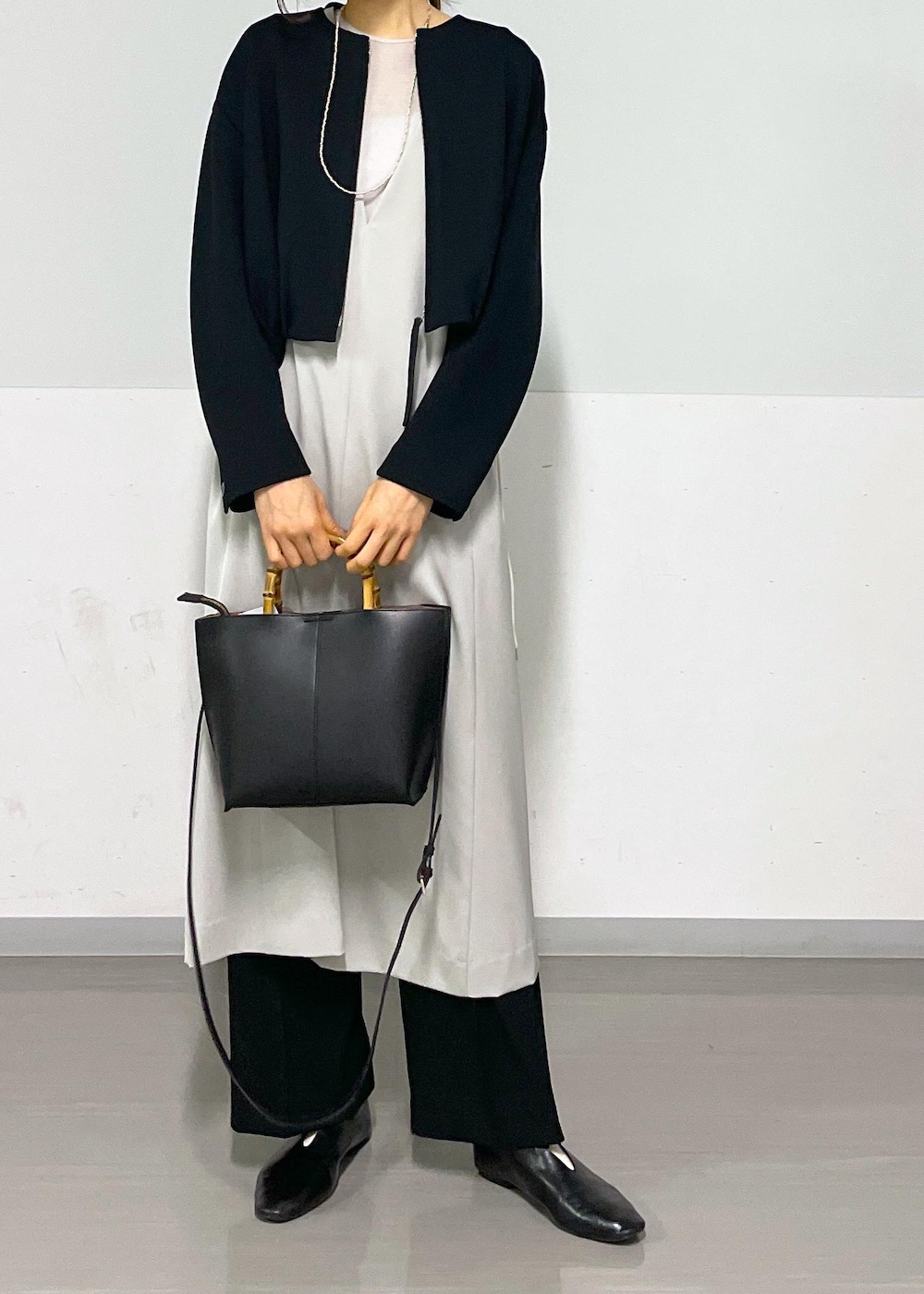 ベージュ系のジャンパースカート、ブラック系のブルゾン、ブラック系のスラックスを着用したレディースの春コーディネートの7枚目の写真