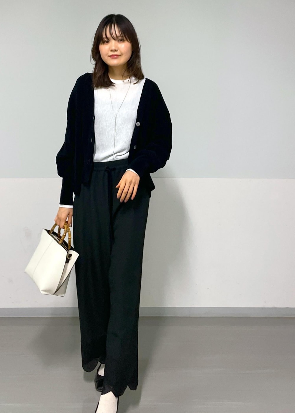 ブラック系のカーディガン/ボレロ、ホワイト系のTシャツ/カットソー、ホワイト系のハンドバッグを着用したレディースの冬コーディネートの7枚目の写真