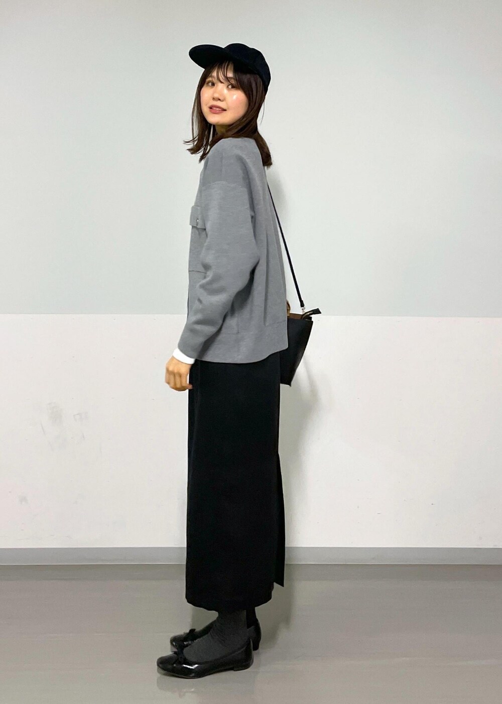 グレー系のカーディガン/ボレロ、ホワイト系のTシャツ/カットソー、ブラック系のハンドバッグを着用したレディースの冬コーディネートの6枚目の写真