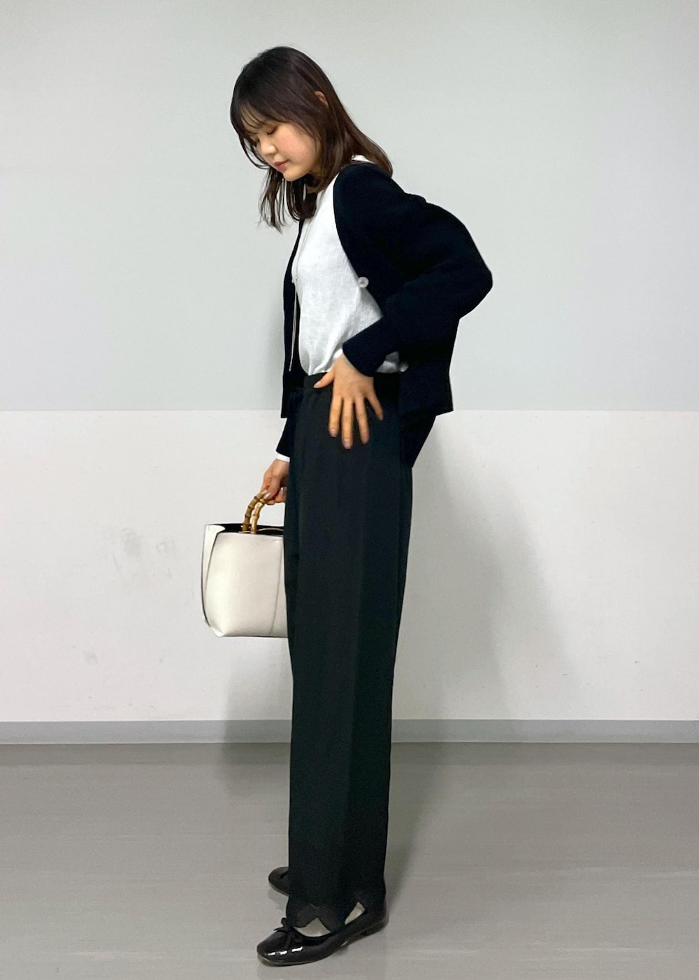 ブラック系のカーディガン/ボレロ、ホワイト系のTシャツ/カットソー、ホワイト系のハンドバッグを着用したレディースの冬コーディネートの4枚目の写真