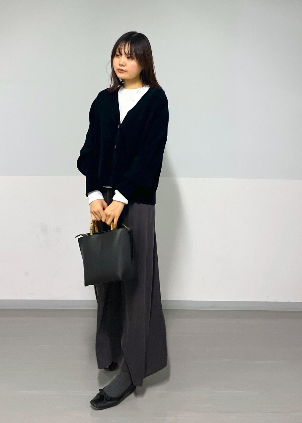 グレー系のスカート、ブラック系のカーディガン/ボレロ、ホワイト系のTシャツ/カットソーを着用したレディースの冬コーディネートの7枚目の写真