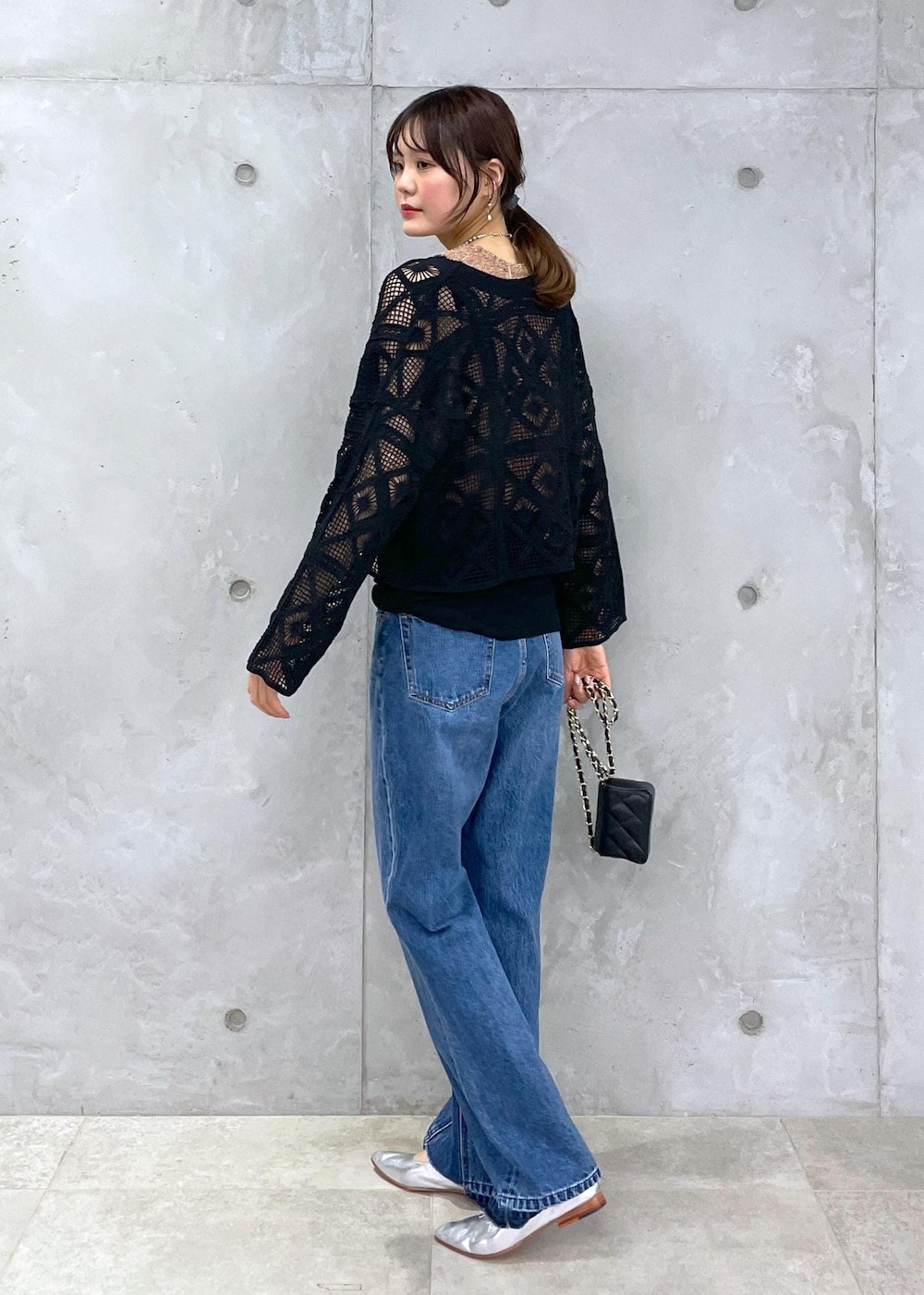 ブラック系のショルダーバッグ、ブルー系のデニムパンツ、ゴールド系のベストを着用したレディースの春コーディネートの8枚目の写真