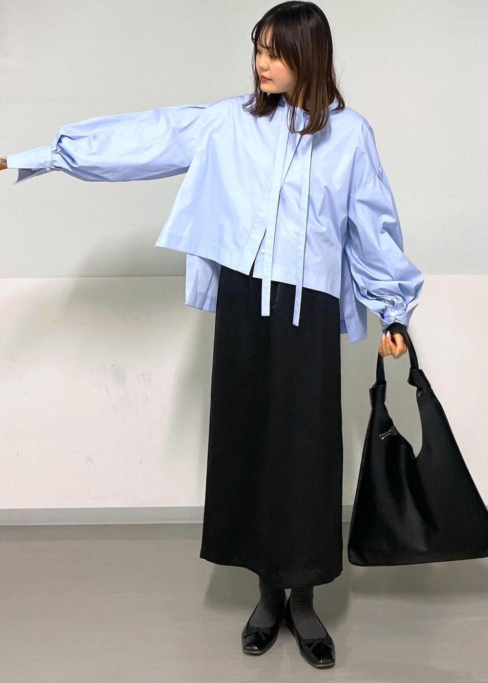 ブルー系のシャツ/ブラウス、ブラック系のトートバッグ、ブラック系のスカートを着用したレディースの冬コーディネートの9枚目の写真