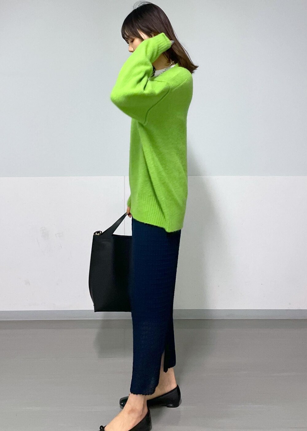 グリーン系のニット/セーター、ホワイト系のTシャツ/カットソー、ブラック系のトートバッグを着用したレディースの冬コーディネートの5枚目の写真