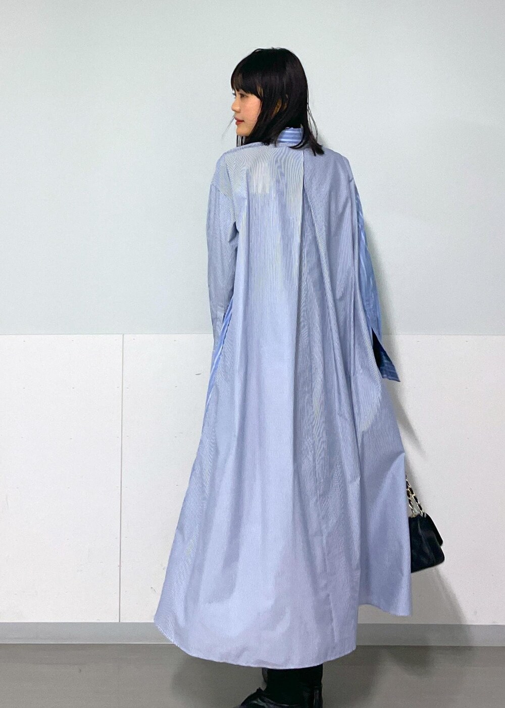 ブラック系のショルダーバッグ、ブルー系のシャツワンピース、ホワイト系のネックレスを着用したレディースの秋コーディネートの7枚目の写真