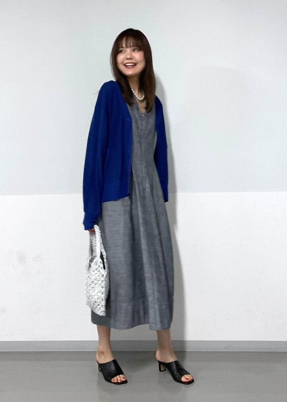 ブラック系のサンダル、ホワイト系のハンドバッグ、ブルー系のカーディガン/ボレロを着用したレディースの夏コーディネートの2枚目の写真