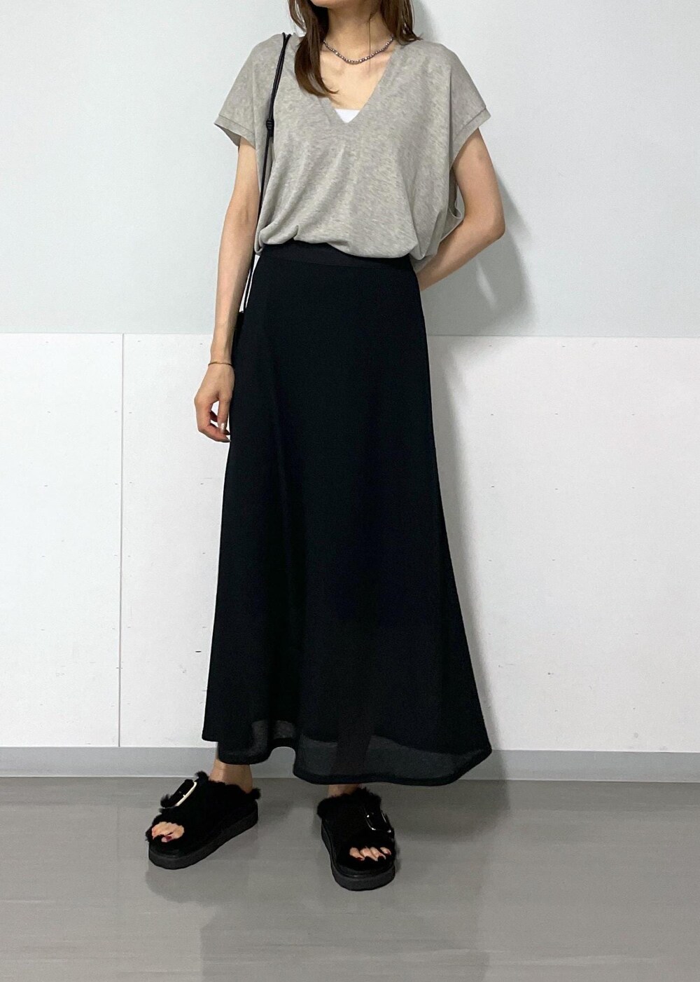 グレー系のタンクトップ、ベージュ系のニット/セーター、ブラック系のスカートを着用したレディースの夏コーディネートの4枚目の写真
