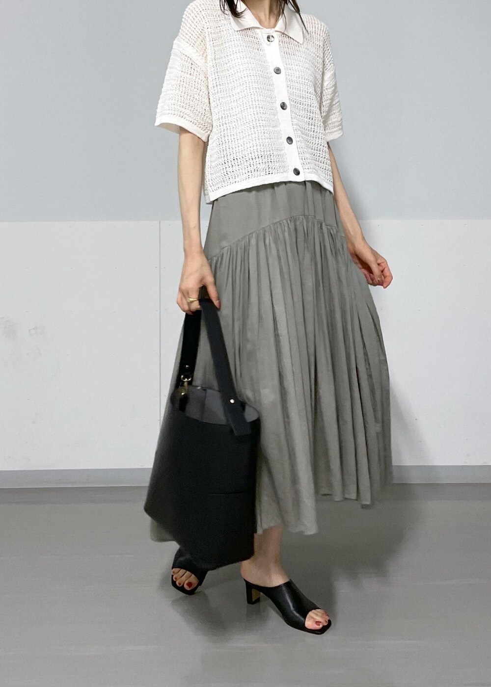 ブラック系のサンダル、ブラック系のトートバッグ、グレー系のスカートを着用したレディースの春コーディネートの5枚目の写真
