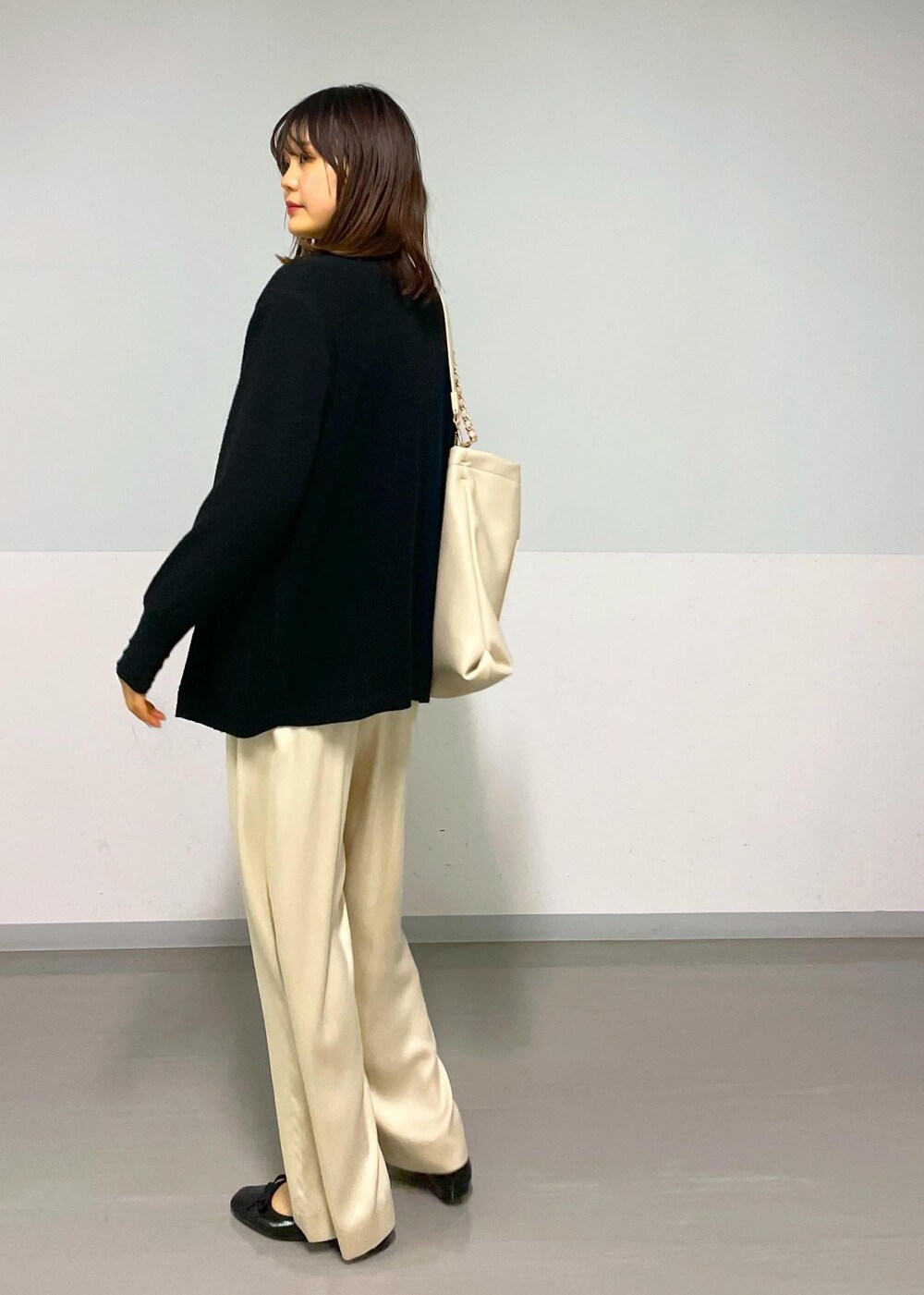 ベージュ系のその他パンツ、ブラック系のカーディガン/ボレロ、ベージュ系のトートバッグを着用したレディースの冬コーディネートの2枚目の写真