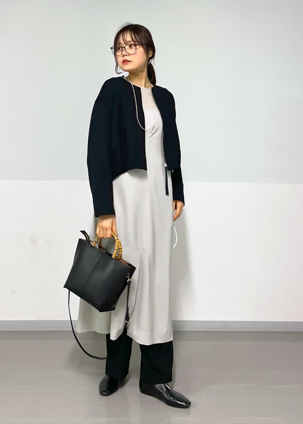 ベージュ系のジャンパースカート、ブラック系のブルゾン、ブラック系のスラックスを着用したレディースの春コーディネートの3枚目の写真