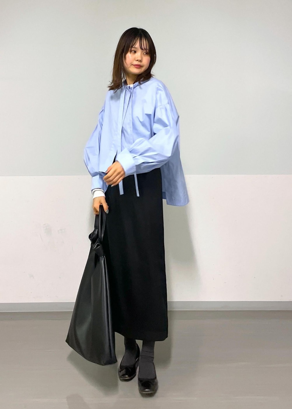 ブルー系のシャツ/ブラウス、ブラック系のトートバッグ、ブラック系のスカートを着用したレディースの冬コーディネートの6枚目の写真
