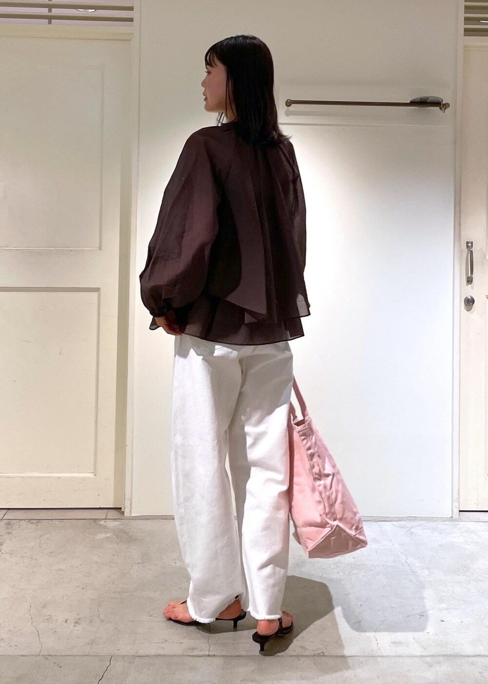 グレー系のタンクトップ、ブラック系のサンダル、ホワイト系のデニムパンツを着用したレディースの夏コーディネートの3枚目の写真