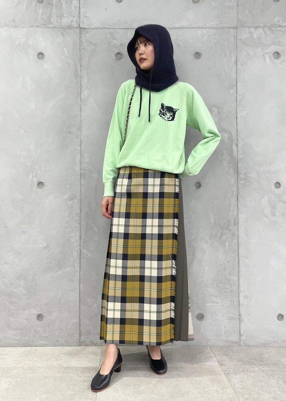 イエロー系のスカート、グリーン系のスウェット、ブラック系のショルダーバッグを着用したレディースの夏コーディネートの2枚目の写真