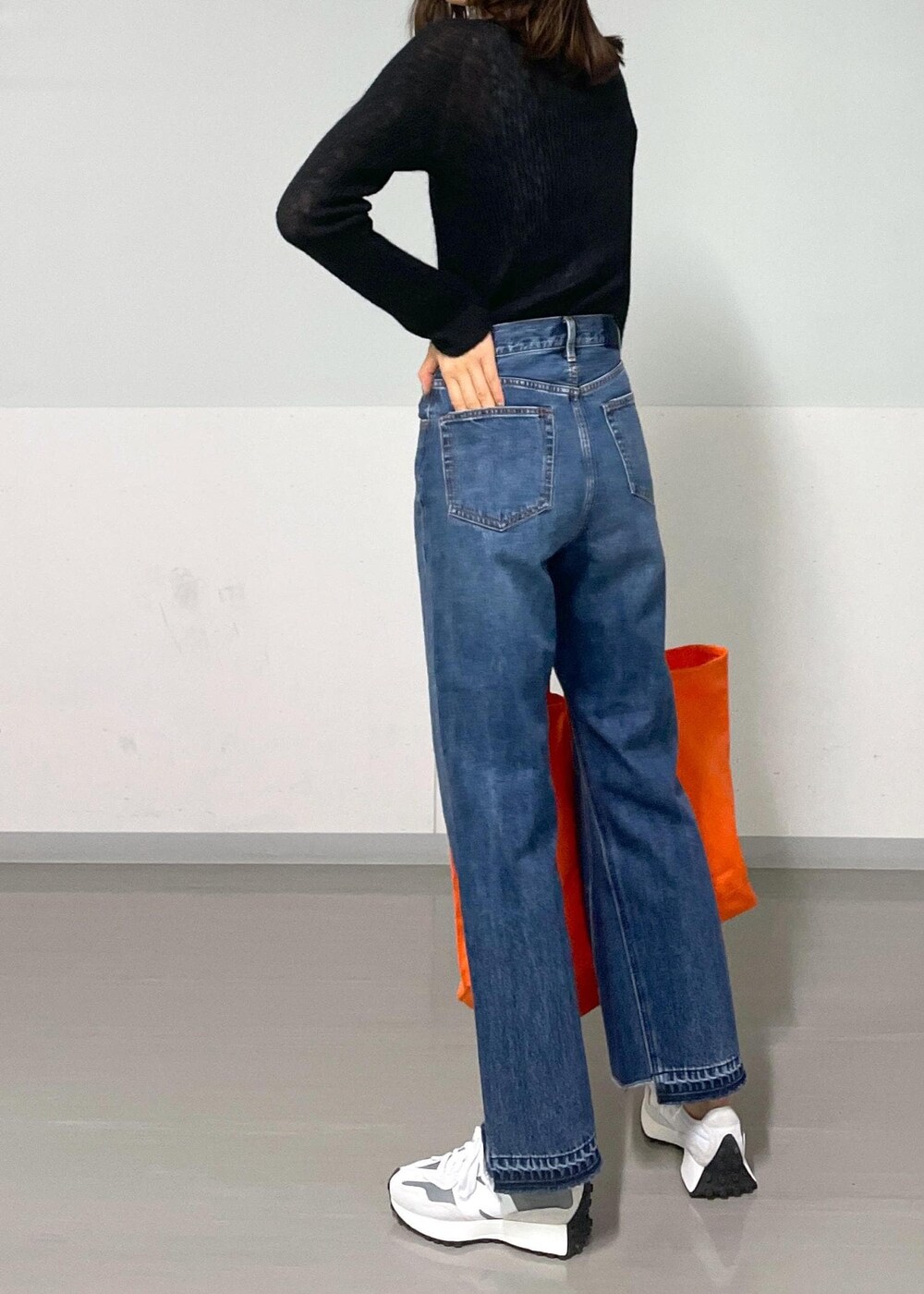 グレー系のタンクトップ、ブラック系のカーディガン/ボレロ、ブルー系のデニムパンツを着用したレディースの秋コーディネートの2枚目の写真