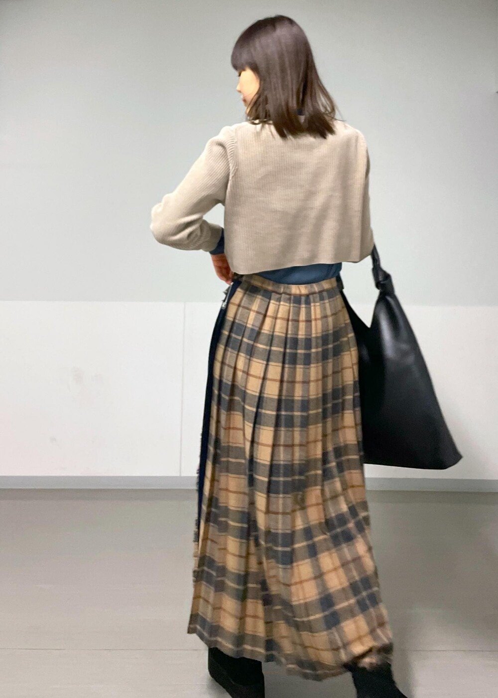 ブルー系のTシャツ/カットソー、ベージュ系のスカート、グレー系のカーディガン/ボレロを着用したレディースの秋コーディネートの2枚目の写真