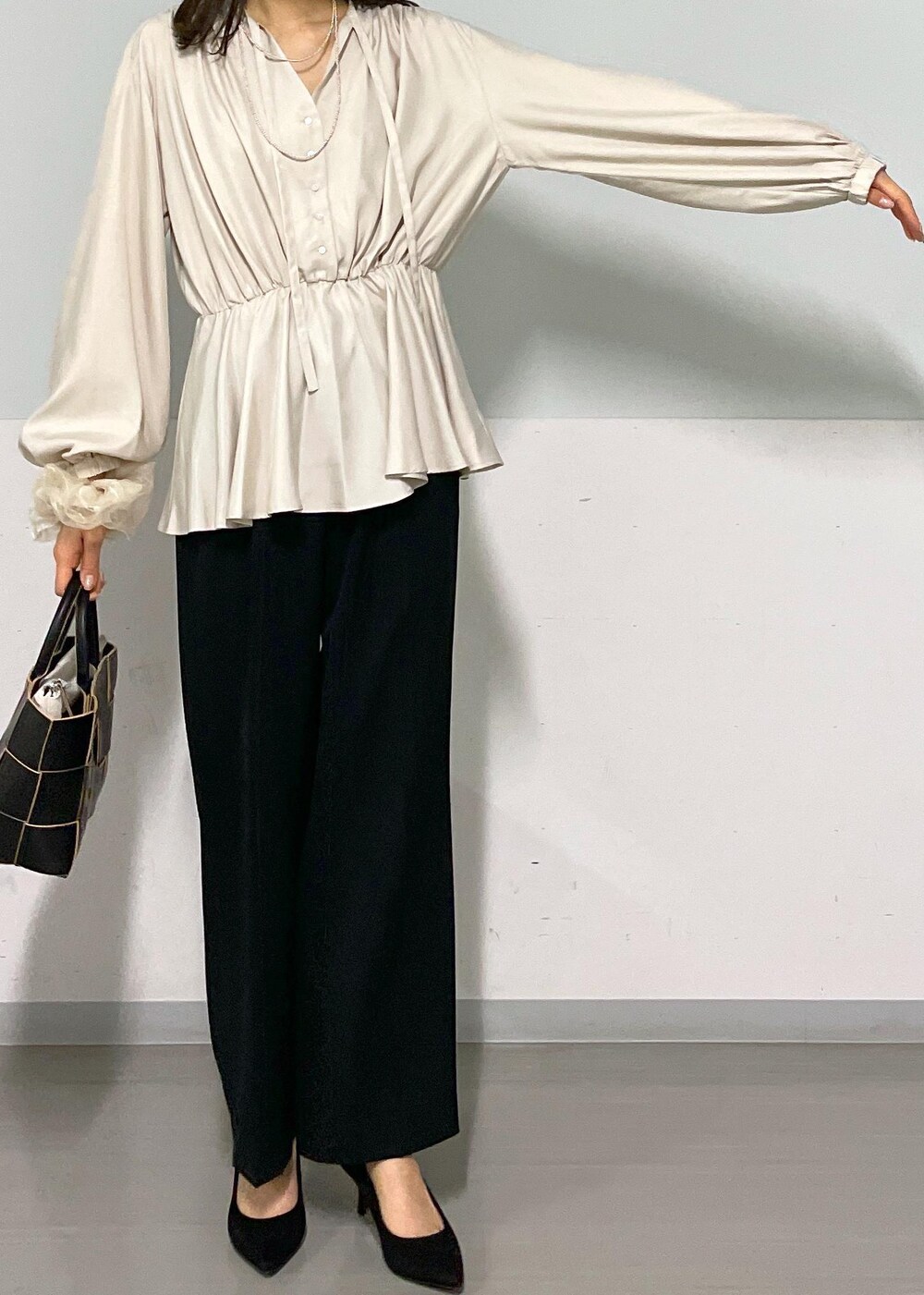 ブラック系のトートバッグ、ブラック系のスラックス、ベージュ系のシャツ/ブラウスを着用したレディースの春コーディネートの6枚目の写真