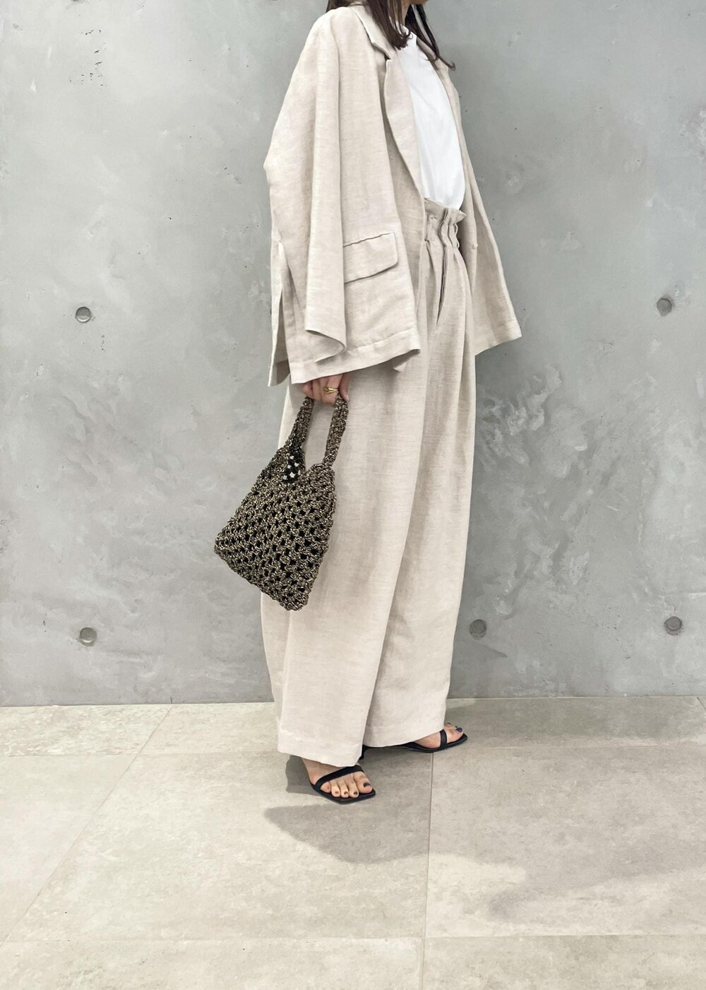 ブラック系のサンダル、ホワイト系のスラックス、ホワイト系のテーラードジャケットを着用したレディースの春コーディネートの3枚目の写真