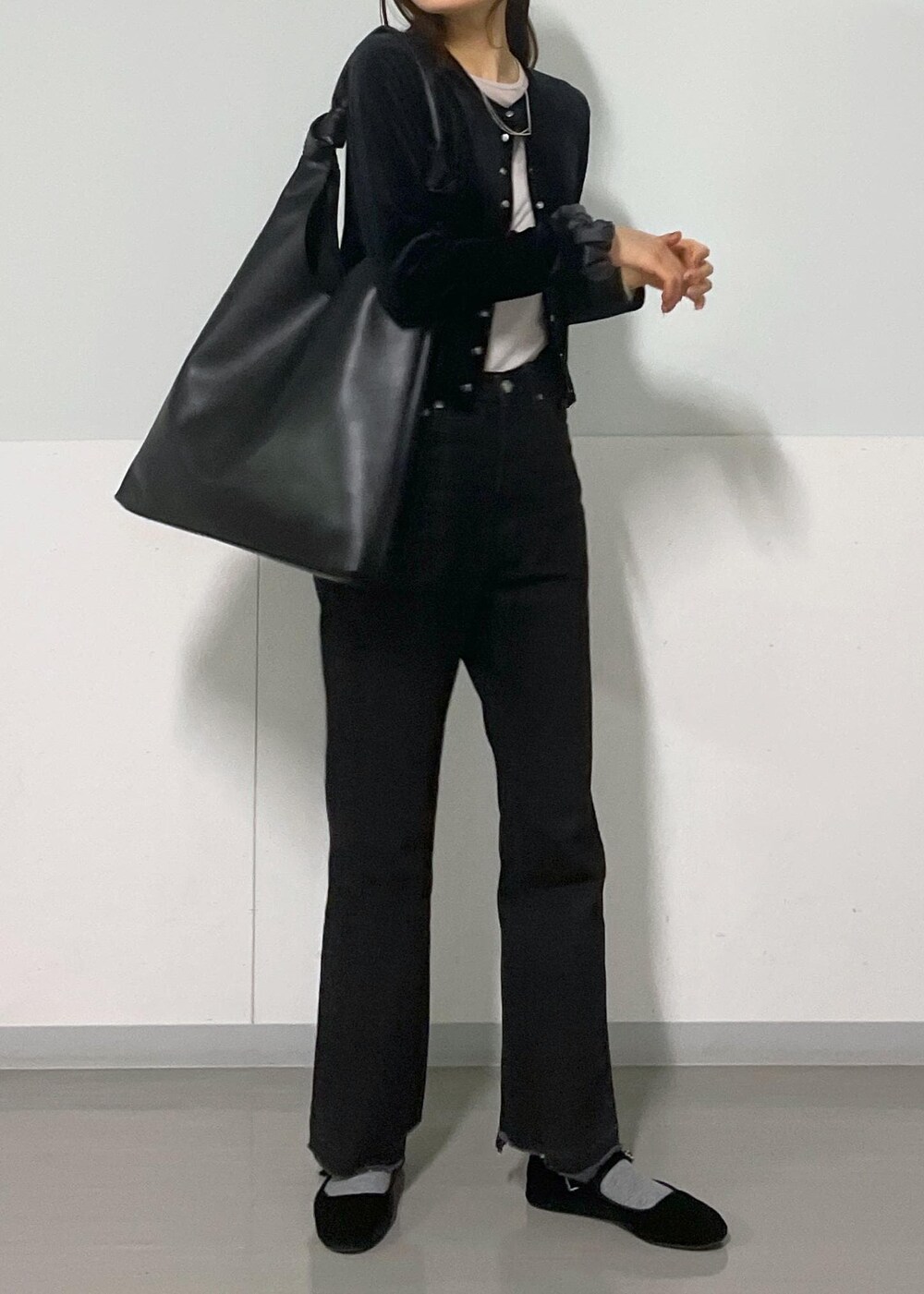 グレー系のTシャツ/カットソー、ブラック系のトートバッグ、グレー系のデニムパンツを着用したレディースの冬コーディネートの4枚目の写真