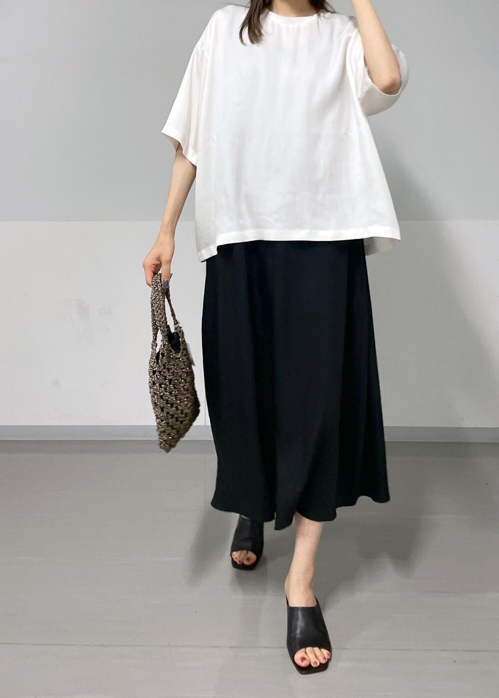 ブラック系のサンダル、ブラック系のハンドバッグ、ホワイト系のTシャツ/カットソーを着用したレディースの夏コーディネートの4枚目の写真