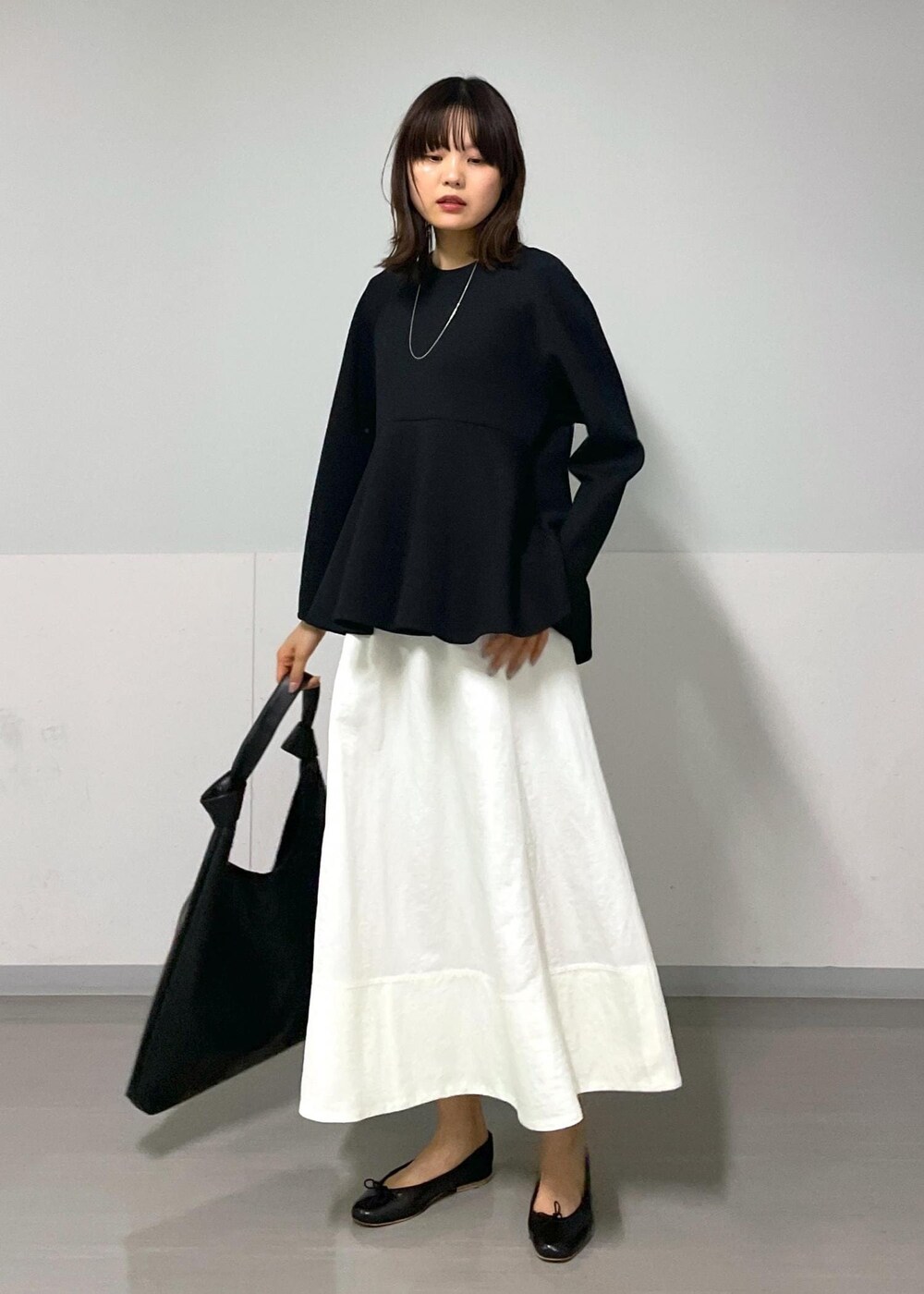 ブラック系のバレエシューズ、ホワイト系のスカート、ブラック系のTシャツ/カットソーを着用したレディースの秋コーディネートの5枚目の写真