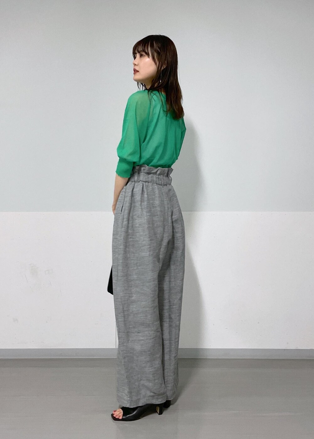 グレー系のタンクトップ、ブラック系のサンダル、グレー系のスラックスを着用したレディースの春コーディネートの2枚目の写真