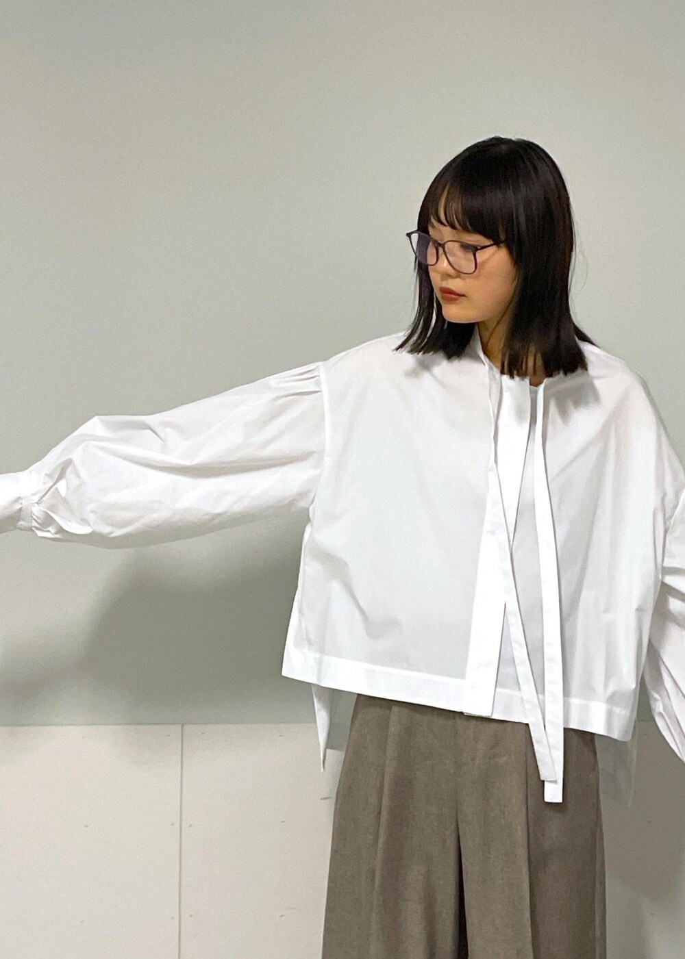 ベージュ系のスラックス、ベージュ系のジャンパースカート、ホワイト系のシャツ/ブラウスを着用したレディースの秋コーディネートの8枚目の写真