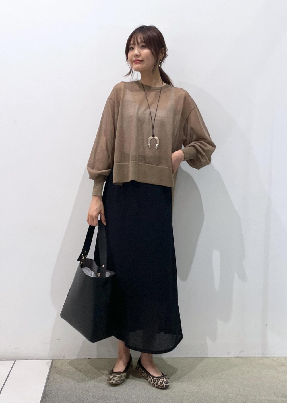 ブラック系のスカート、ゴールド系のTシャツ/カットソー、ブラック系のトートバッグを着用したレディースの夏コーディネートの2枚目の写真