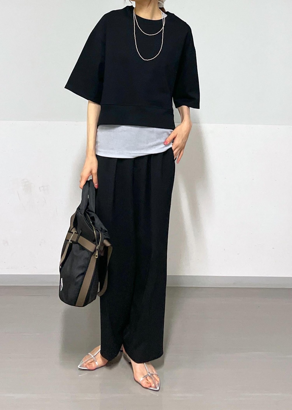 ブラック系のスラックス、シルバー系のサンダル、ブラック系のトートバッグを着用したレディースの夏コーディネートの5枚目の写真