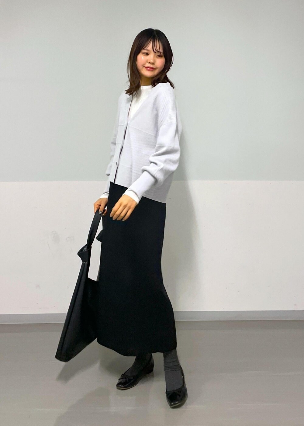 ブラック系のトートバッグ、ホワイト系のTシャツ/カットソー、グレー系のカーディガン/ボレロを着用したレディースの冬コーディネートの7枚目の写真