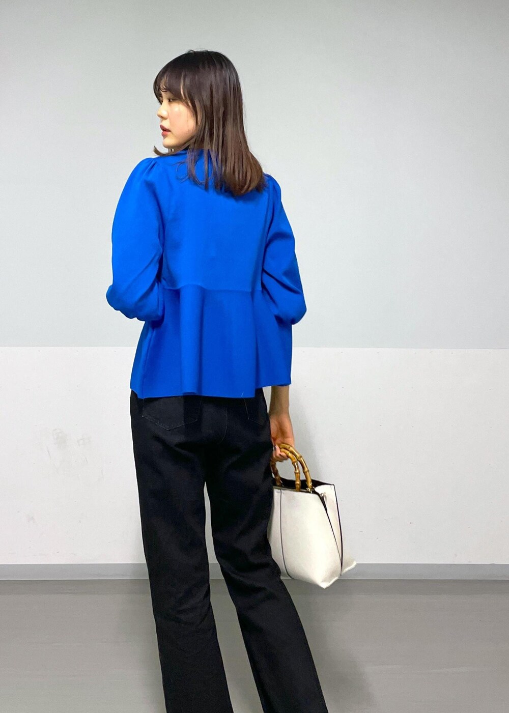グレー系のデニムパンツ、ホワイト系のハンドバッグ、ブルー系のカーディガン/ボレロを着用したレディースの冬コーディネートの5枚目の写真