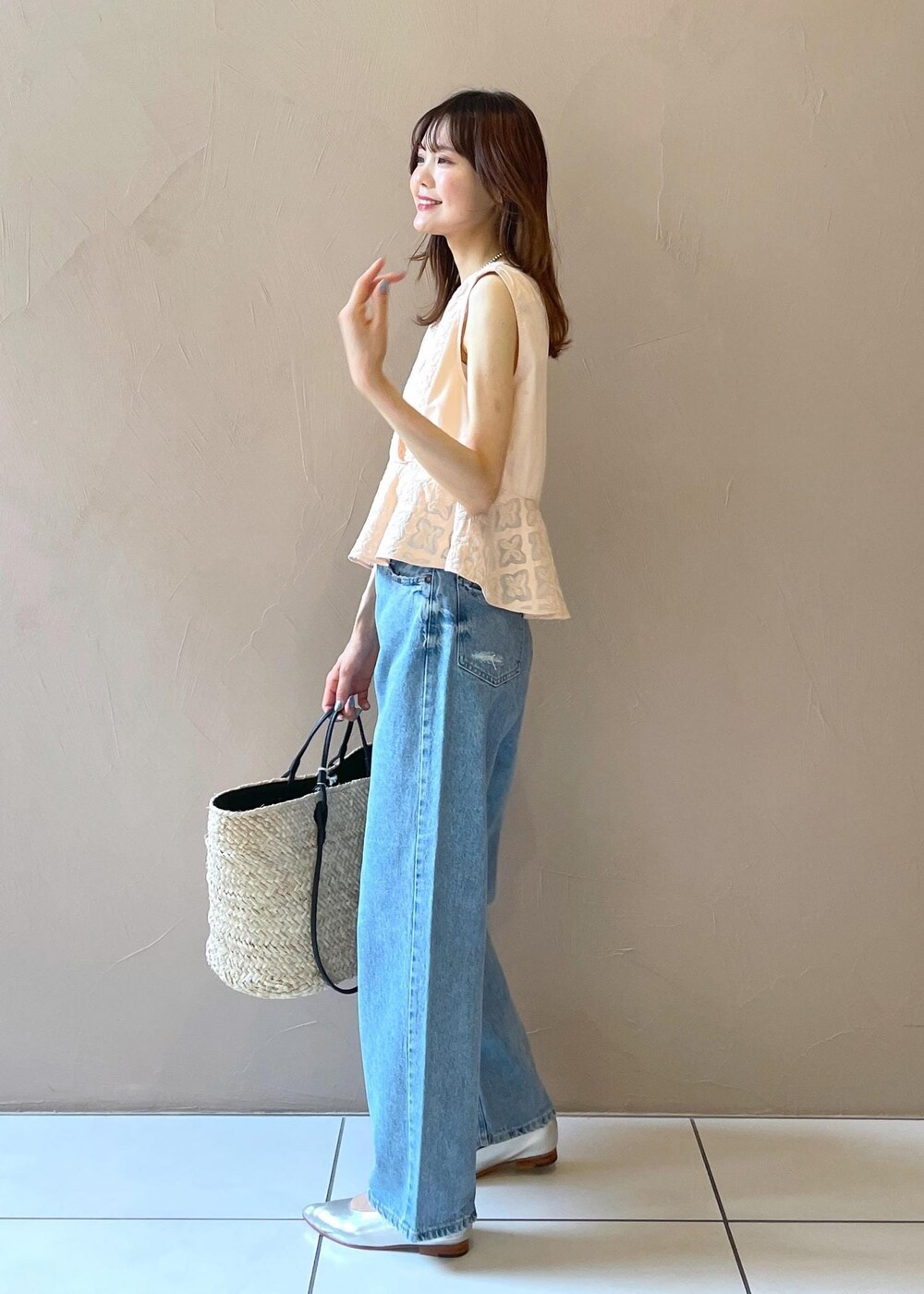 ホワイト系のかごバッグ、ブルー系のデニムパンツ、シルバー系のパンプスを着用したレディースの夏コーディネートの6枚目の写真