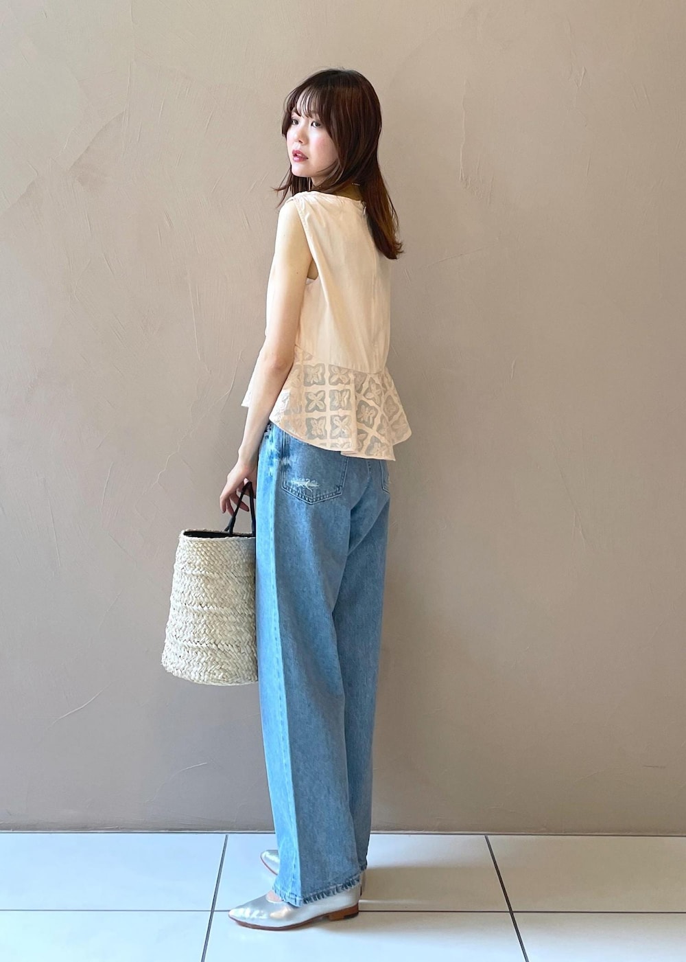 ホワイト系のかごバッグ、ブルー系のデニムパンツ、シルバー系のパンプスを着用したレディースの夏コーディネートの2枚目の写真