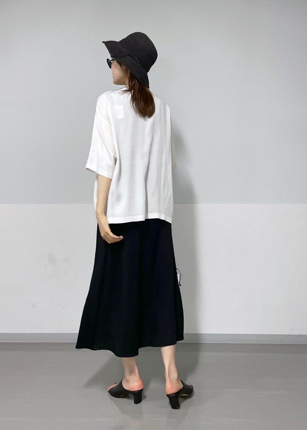 ブラック系のサンダル、ブラック系のハンドバッグ、ホワイト系のTシャツ/カットソーを着用したレディースの夏コーディネートの3枚目の写真