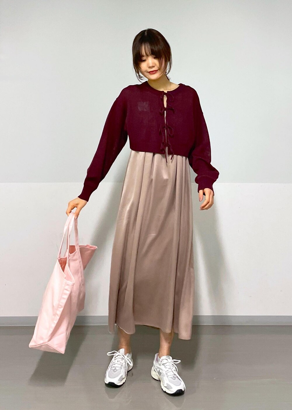 レッド系のニット/セーター、イエロー系のワンピース、ホワイト系のスニーカーを着用したレディースの春コーディネートの3枚目の写真