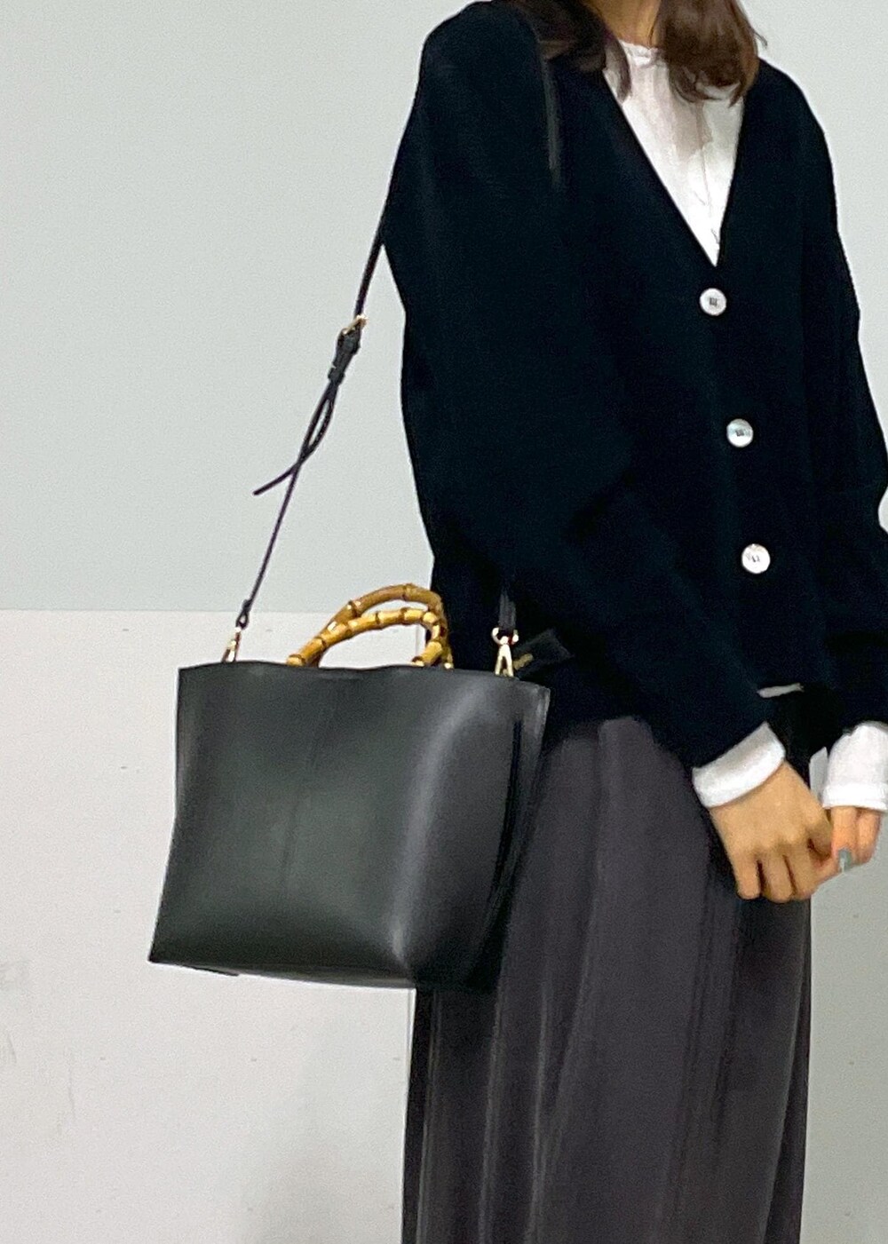 グレー系のスカート、ブラック系のカーディガン/ボレロ、ホワイト系のTシャツ/カットソーを着用したレディースの冬コーディネートの9枚目の写真