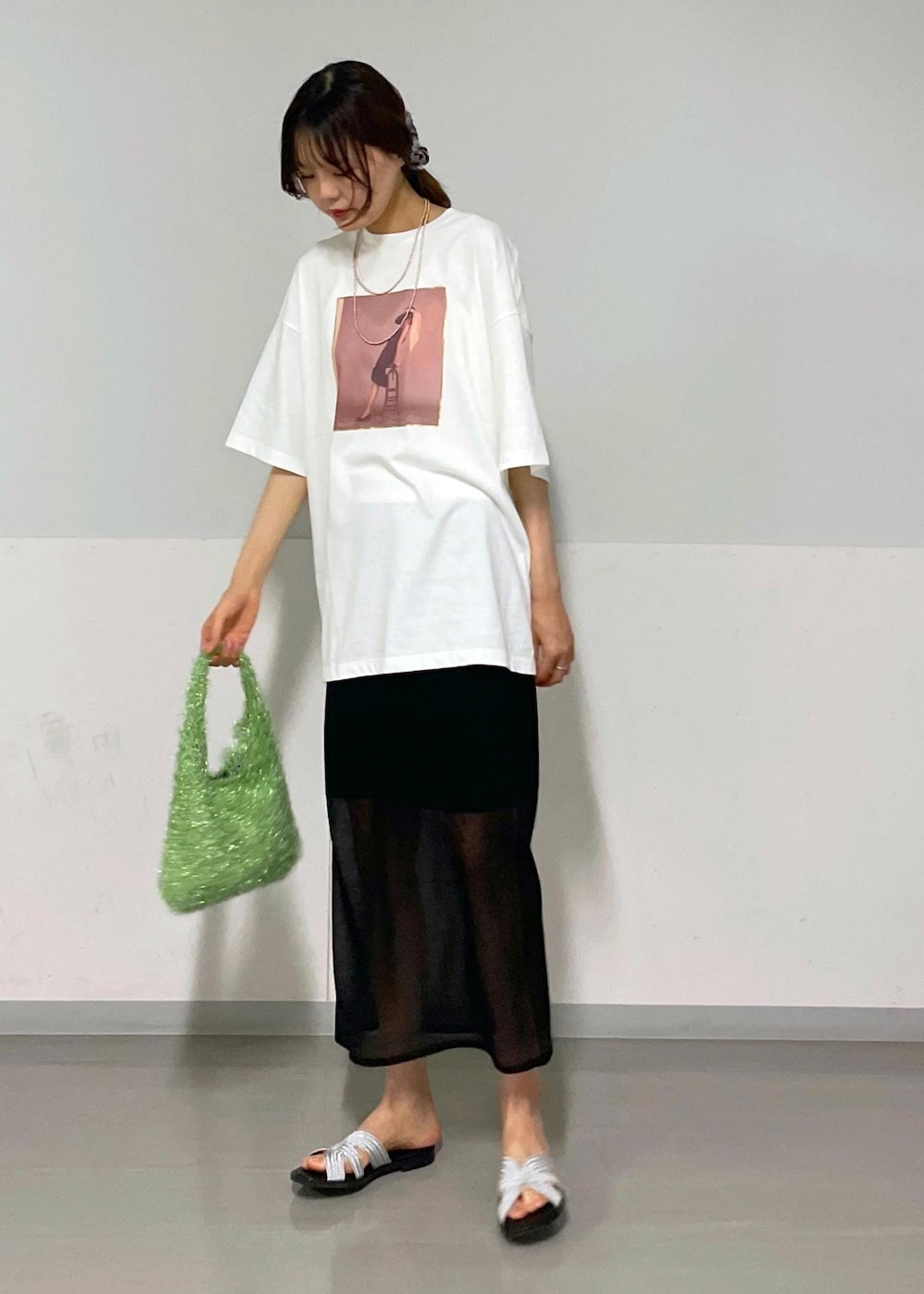 ブラック系のスカート、グリーン系のハンドバッグ、ホワイト系のTシャツ/カットソーを着用したレディースの夏コーディネートの6枚目の写真
