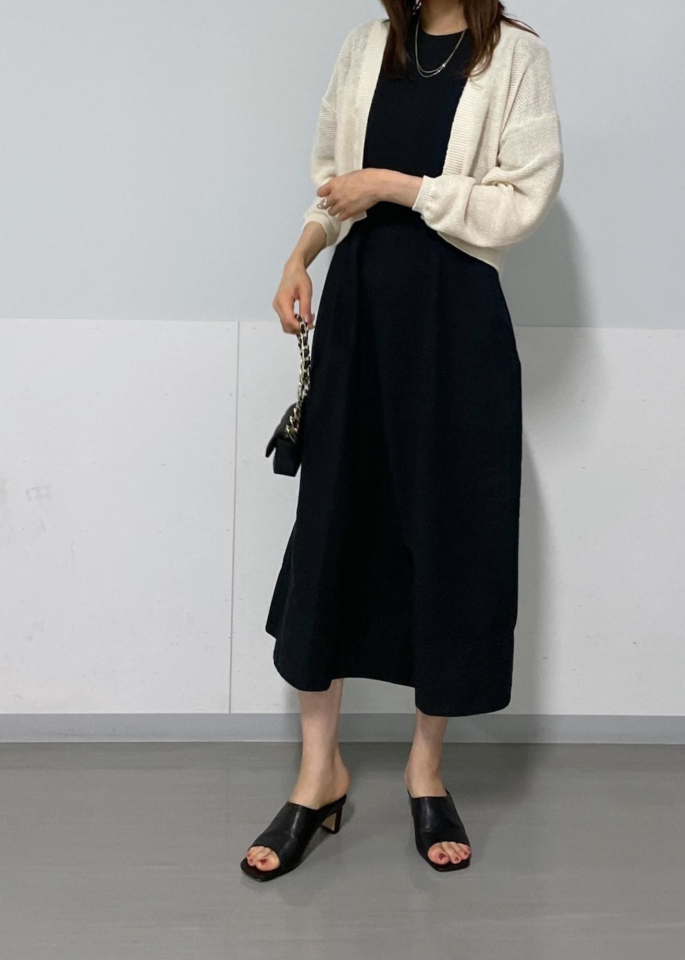 ブラック系のサンダル、ホワイト系のカーディガン/ボレロ、ブラック系のワンピースを着用したレディースの夏コーディネートの7枚目の写真