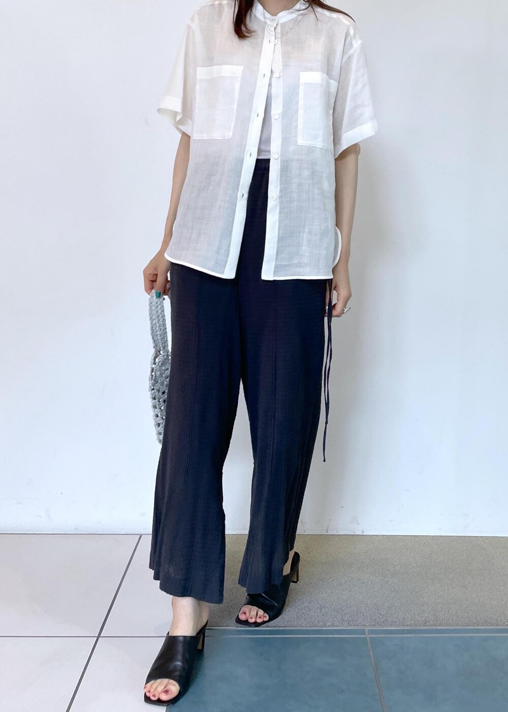 ブラック系のサンダル、グレー系のタンクトップ、ホワイト系のハンドバッグを着用したレディースの夏コーディネートの2枚目の写真