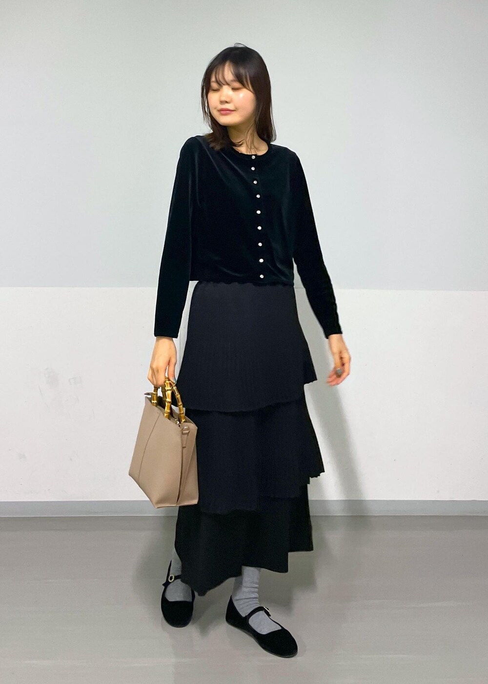 ブラック系のカーディガン/ボレロ、ブラック系のスカート、ベージュ系のハンドバッグを着用したレディースの冬コーディネートの3枚目の写真