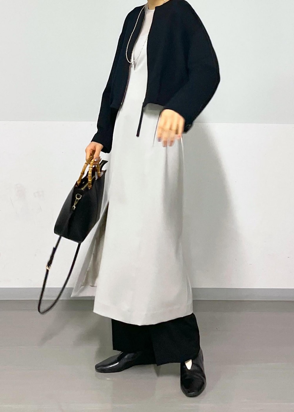 ベージュ系のジャンパースカート、ブラック系のブルゾン、ブラック系のスラックスを着用したレディースの春コーディネートの5枚目の写真