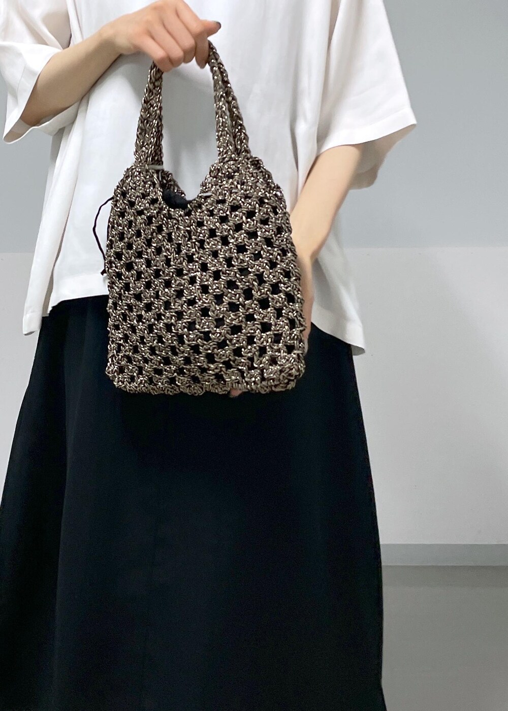 ブラック系のサンダル、ブラック系のハンドバッグ、ホワイト系のTシャツ/カットソーを着用したレディースの夏コーディネートの6枚目の写真