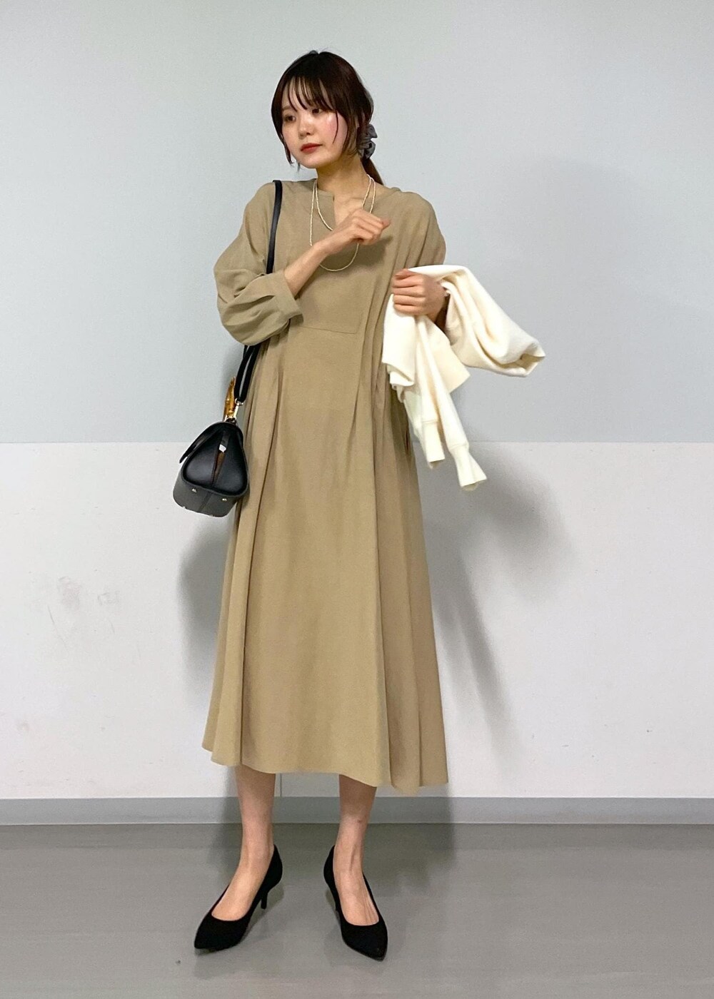 ブラック系のショルダーバッグ、ベージュ系のワンピース、ホワイト系のカーディガン/ボレロを着用したレディースの春コーディネートの8枚目の写真
