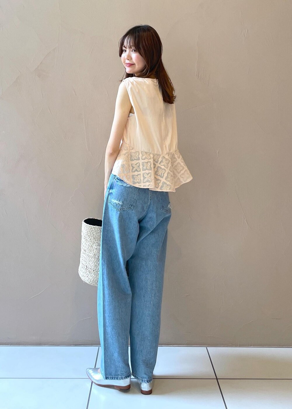 ホワイト系のかごバッグ、ブルー系のデニムパンツ、シルバー系のパンプスを着用したレディースの夏コーディネートの7枚目の写真