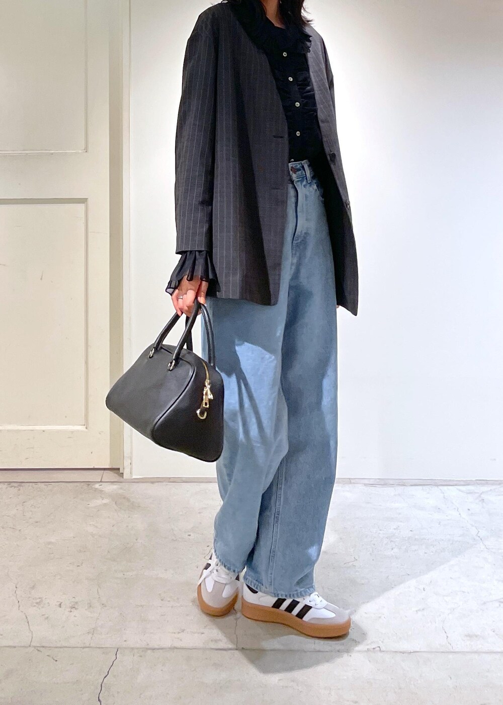 グレー系のノーカラージャケット、ブルー系のデニムパンツ、ブラック系のボストンバッグを着用したレディースの夏コーディネートの6枚目の写真