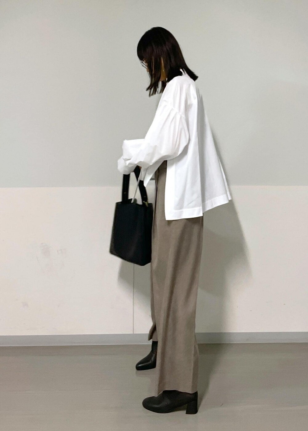 ベージュ系のスラックス、ベージュ系のジャンパースカート、ホワイト系のシャツ/ブラウスを着用したレディースの秋コーディネートの6枚目の写真