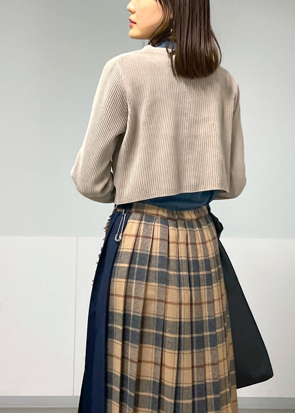ブルー系のTシャツ/カットソー、ベージュ系のスカート、グレー系のカーディガン/ボレロを着用したレディースの秋コーディネートの5枚目の写真